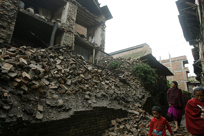 People walk past collapsed buildings damaged by an earthquake that shook northeastern India on Sunday night, in Katmandu, Nepal, Monday, Sept. 19, 2011. The 6.9-magnitude quake shook the Himalayan region straddling India, Nepal and China. (AP Photo/Binod Joshi)