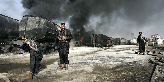 Pakistani police gather evidence beside still smoldering oil trucks in Shikarpur, southern Pakistan on Friday Oct. 1, 2010. Suspected militants set ablaze at least 27 tankers carrying fuel for U.S. and NATO troops in Afghanistan on Friday, police said. (AP Photo/Aaron Favila)