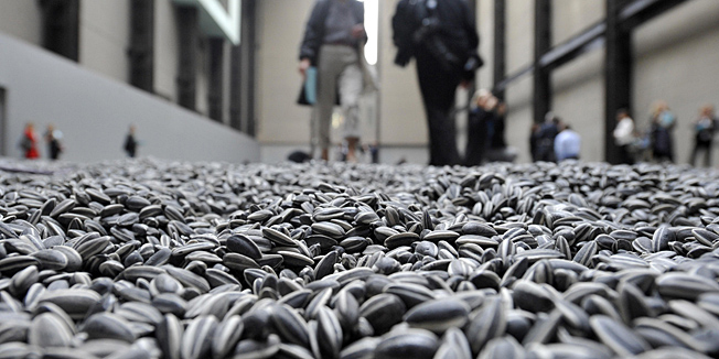 Visitors walk through the art installation 'Sunflower Seeds' by Chinese artist Ai Weiwei  in London, Monday, Oct. 11, 2010. The specially commissioned art piece takes the form of a field of sunflower seeds inside the Turbine Hall at Tate Modern gallery,  made of over 100 million handmade unique porcelain replicas of sunflower seeds, made by Chinese Artist Ai Weiwei, and will run until May 2, 2011. (AP Photo/Lennart Preiss)