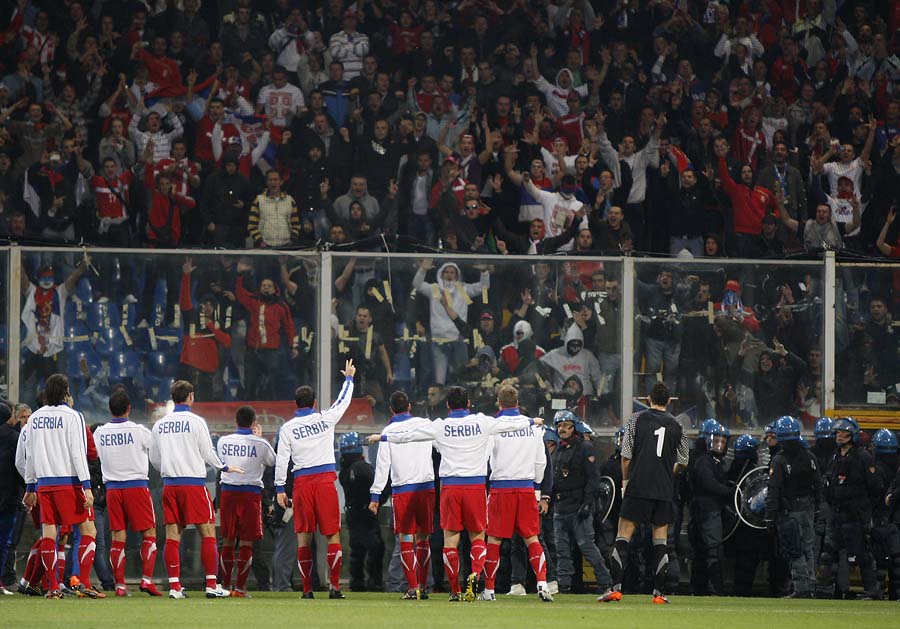 Serbia players gesture to Serbia fans prior to the start of a Group C, Euro 2012 qualifying soccer match between Italy and Serbia, at the Luigi Ferraris stadium in Genoa, Italy, Tuesday, Oct. 12, 2010. The Italy-Serbia European Championship qualifier has been stopped after seven minutes of play due to Serbia fans throwing flares onto the pitch and lighting fireworks. At one point during the delay, the Serbia squad walked over and appeared to applaud their fans ironically and ask them to calm down. (AP Photo/Antonio Calanni)