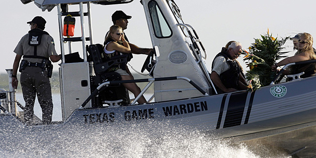 Tiffany Hartley, center next to driver, and family members, are escorted by the Texas Parks and Wildlife Department with a wreath to the site her husband, David Hartley, was shot last week, on Falcon Lake, Wednesday, Oct. 6, 2010 in Zapata, Texas. Hartman was shot by Mexican pirates on Falcon Lake last week as they were returning to the United States on Jet Skis.(AP Photo/Eric Gay)