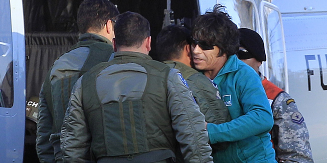 Rescued miner Johnny Barrios, 50, right, is embraced by a member of the Air Force as he arrives at an army airfield in Copiapo, Chile, Wednesday, Oct. 13, 2010. Barrios is the twenty first of 33 miners rescued from the San Jose mine after more than two months trapped underground. (AP Photo/Martin Mejia)