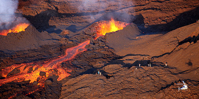 Aerial view taken on October 15, 2010 of a chopper flying over lava streams flowing out of the Piton de la Fournaise volcano on the French island of la Reunion in the Indian ocean. The eruption took place on October 14, 2010 near the 