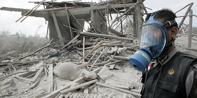 A rescuer stands at a village hit by pyroclastic flows from Tuesday's eruption of Mount Merapi in Kinahrejo, Yogyakarta, Indonesia, Wednesday, Oct. 27, 2010. The volcanic eruption and a tsunami killed scores of people hundreds of miles apart in Indonesia, spasms from the Pacific 