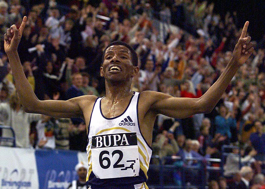 FILE - In this  Sunday Feb.  14, 1999 file photo Haile Gebrselassie, of Ethiopia, holds his arms aloft as he crosses the finish line to break the world indoor record for 5000 meters at the National Indoor Arena in Birmingham, England. Fortunately for the New York City Marathon, Haile Gebrselassie won't even talk about retirement. The 37-year-old Ethiopian _ widely considered the greatest distance runner ever _ has set a host of world records, won two Olympics golds and captured eight world titles in events ranging from the 1,500 meters right up to the marathon. Now, for the first time, he is running in New York's marathon. Seventeen years after his first world title, he says he's in no mood to wind down his incredible career.  (AP Photo/Louisa Buller, file)