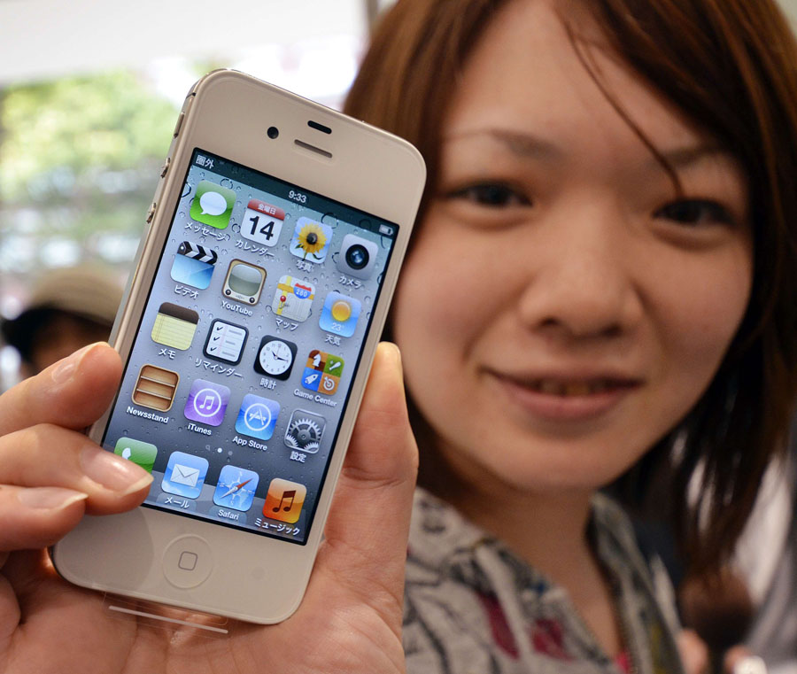 A customer holds up her newly bought Apple iPhone 4S on the day of its release outside a Softbank shop in Tokyo on October 14, 2011. Hundreds of Apple fans queued in Tokyo to get their hands on the latest iPhone, as the US technology giant unleashes its first device since the death of co-founder Steve Jobs.   AFP PHOTO / Yoshikazu TSUNO