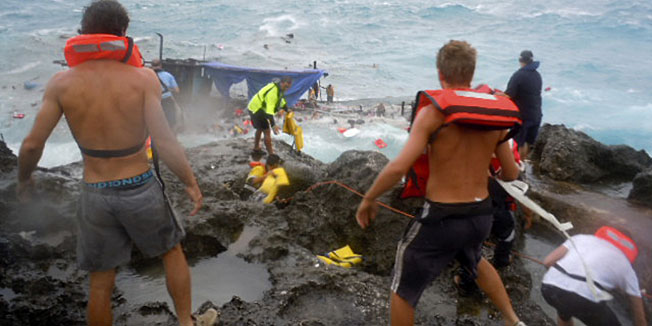 People clamber on the rocky shore on Christmas Island during a rescue attempt as a boat breaks up in the background Wednesday, Dec. 15, 2010. A wooden boat packed with dozens of asylum seekers smashed apart on cliff-side rocks in heavy seas off an Australian island Wednesday, sending some to their deaths in churning whitewater. (AP Photo/ABC) AUSTRALIA OUT