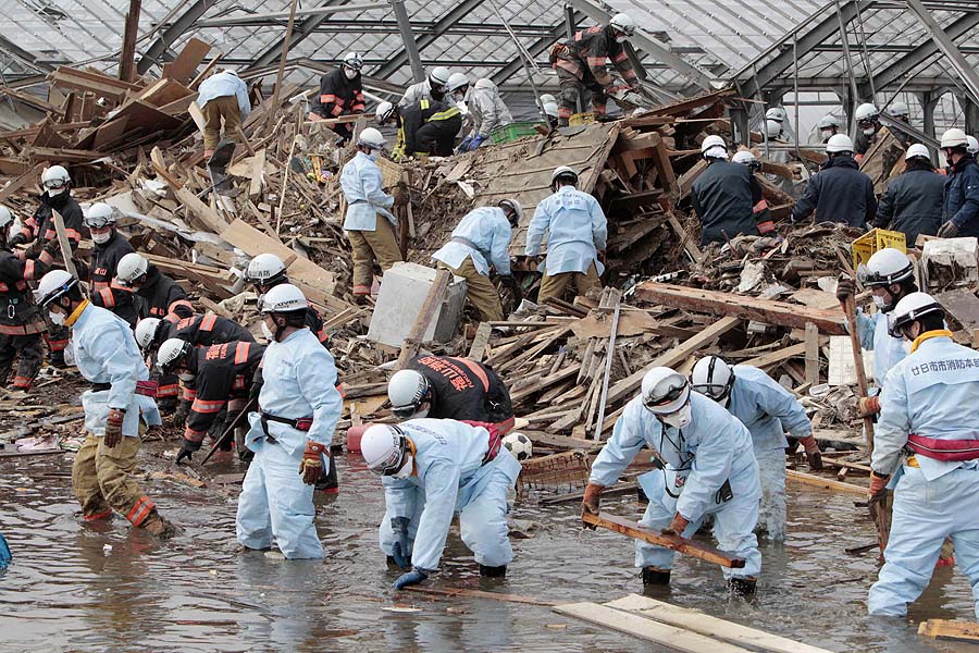 Rescuers sift through the remains of a property in the suburb of Natori, Miyagi Prefecture, Japan, Sunday, March 20, 2011 after the March 11 earthquake and tsunami devastated the area. (AP Photo/Mark Baker)