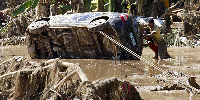 Residents retrieve a car which was washed away in Friday's flash flooding in Iligan city in southern Philippines Monday Dec. 19, 2011. With funeral parlors overwhelmed, authorities in a flood-stricken southern Philippine city organized the first mass burial of unidentified victims who were swept to their deaths in one of the worst calamities to strike the region in decades. (AP Photo/Bullit Marquez)