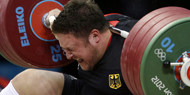 Matthias Steiner of Germany gets hit by the weights while failing to make a successful lift  in the men's over 105-kg, group A, weightlifting competition at the 2012 Summer Olympics, Tuesday, Aug. 7, 2012, in London. (AP Photo/Mike Groll)