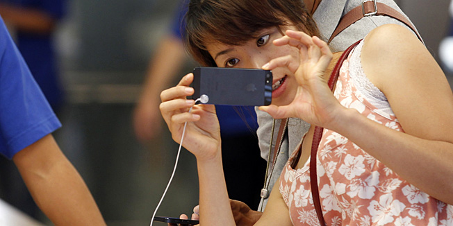 A customer checks Apple's iPhone 5 at a store in Tokyo Friday morning, Sept. 21, 2012. Apples Asian fans jammed the tech juggernauts shops in Australia, Hong Kong, Japan and Singapore to pick up the latest version of its iPhone. (AP Photo/Koji Sasahara)