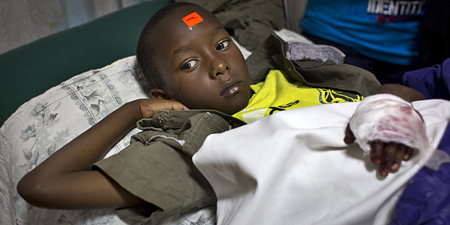 Malcolm Murage, 9, whose left hand was injured in an explosion at a Sunday school class and who wears an orange triage label on his forehead, is treated in Kenyatta National Hospital in Nairobi, Kenya Sunday, Sept. 30, 2012. An explosive device set off in a Sunday school class killed one child and seriously wounded three, according to Nairobi's acting police chief, who said said he suspects sympathizers with the Somali militant group al-Shabab were behind the attack at the Anglican church. (AP Photo/Ben Curtis)