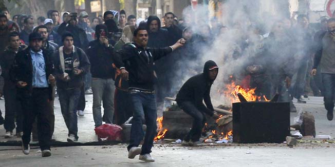 Demonstrators  throws stones at police during clashes in Tunis, Friday, Jan. 14, 2011. Tunisia's president declared a state of emergency and announced that he would fire his government as violent protests escalated Friday, with gunfire echoing in the North African country's usually calm capital and police lobbing tear gas at protesters. (AP Photo/Christophe Ena)