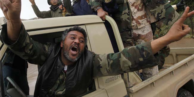 CORRECTS SPELLING OF GADHAFI IN FIRST REFERENCE AND LIBYAN  Anti-Libyan leader Moammar Gadhafi gunmen celebrate the freedom of the Libyan city of Benghazi, Libya, on Sunday Feb. 27, 2011. US President Barack Obama has called on Libyan dictator Moammar Gadhafi to leave power immediately, saying he has lost the legitimacy to rule with his violent crackdown on his own people. (AP Photo/Hussein Malla)