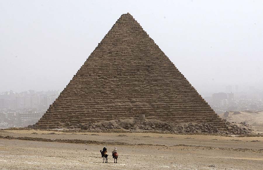 Tow tourist guides ride their camels at the Giza pyramids on the outskirts of Cairo, Egypt,  Sunday Feb. 20,  2011. The pyramids were virtually deserted on Sunday, symbols of the severe blow to the tourism industry that Egypt has suffered in the wake of the upheaval that toppled President Hosni Mubarak on Feb. 11.(AP Photo/Khalil Hamra)