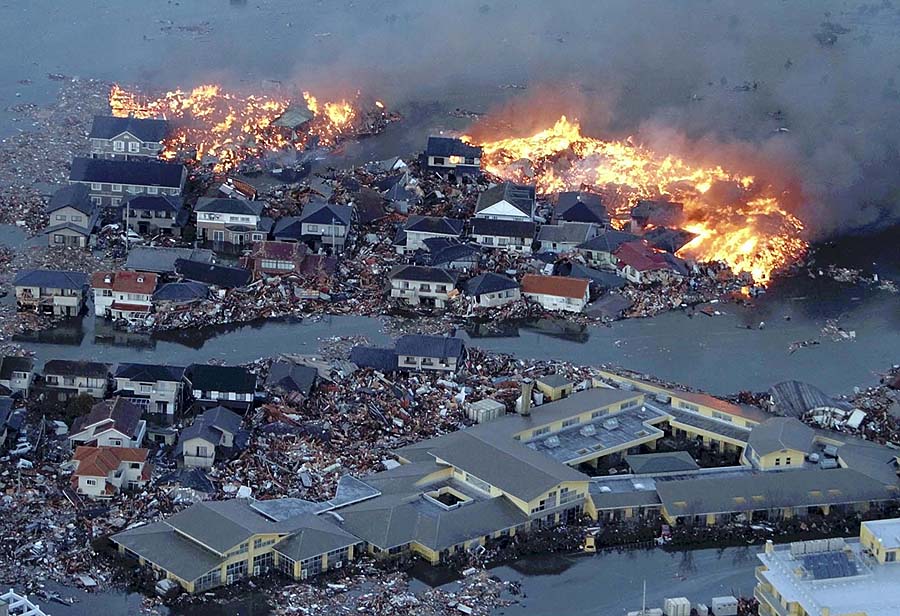 Houses are shown in flame while the Natori river floods over the surrounding area by tsunami tidal waves in Natori city, Miyagi Prefecture, northern Japan, March 11, 2011, after strong earthquakes hit the area. (AP Photo/Yasushi Kanno, The Yomiuri Shimbun)  JAPAN OUT, CREDIT MANDATORY