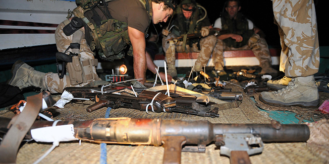 In this image made available by the Ministry of Defence in London, Thursday Feb. 16, 2011, members of a naval boarding party from HMS Cornwall uncover arms and ammunition during a search of a Somali pirate dhow in the Indian Ocean on Thursday Feb. 10, 2011. The vessel was boarded after was spotted acting suspiciously by a South Korean merchant vessel, the Yong Jin, which made a call for help to the British warship. Five hostages and their fishing vessel were released, and an initial search discovered AK47's, a grenade launcher, rocket propelled grenades and large amounts of ammunition.(AP Photo/Dave Jenkins, Ministry of Defence, ho)  EDITORIAL USE ONLY: