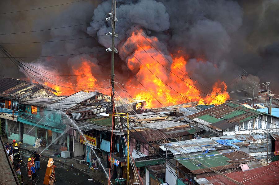 Firemen battle to control a fire raging through informal settlers' homes in theMakati financial district of Manila on April 19, 2011. The fire razed a sprawling residential compound in the Philippine capital's financial district leaving up to 10,000 people homeless, authorities said. AFP PHOTO/NOEL CELIS