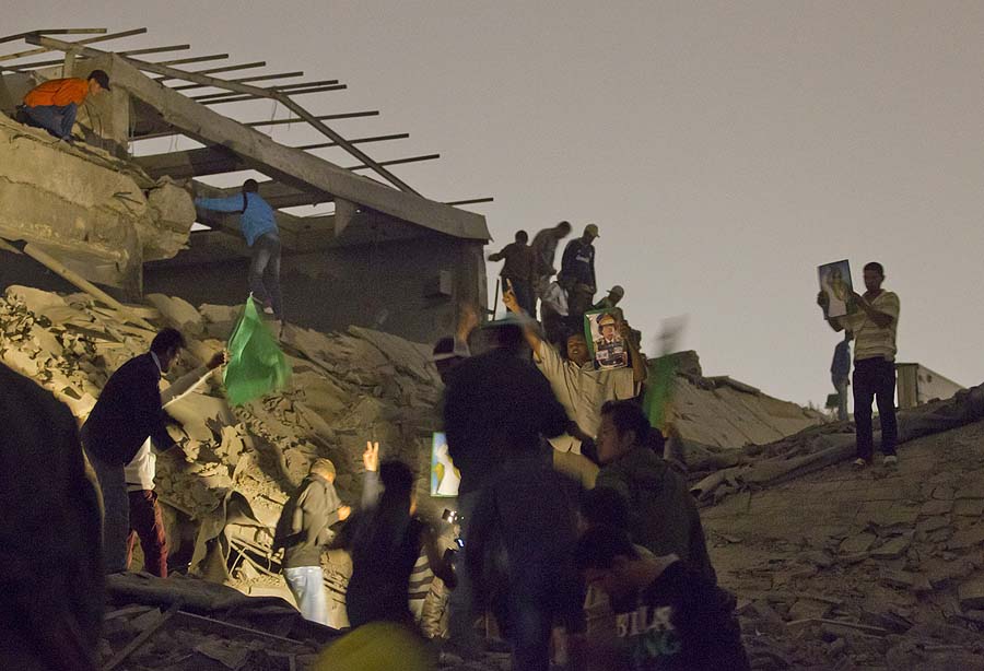 In this photo made on a government organized trip, Moammar Gadhafi supporters inspect damage following an airstrike in Tripoli, Libya, early Monday, April 25, 2011. The airstrike on Gadhafi's sprawling residential compound early Monday badly damaged two buildings, including a structure where Gadhafi often held meetings, guards at the complex said. (AP Photo/Darko Bandic)