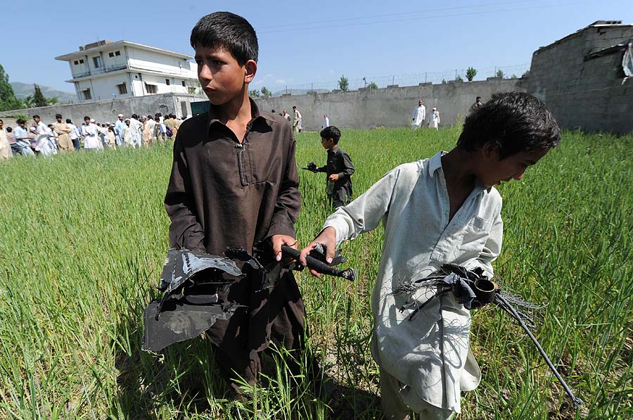 Pakistani boys collect debris at the site of the crashed helicopter outside the hideout house of Al-Qaeda leader Osama bin Laden following his death by US Special Forces in a ground operation in Abbottabad on May 3, 2011. The bullet-riddled Pakistani villa that hid Osama bin Laden from the world was put under police control, as media sought to glimpse the debris left by the US raid that killed him. Bin Laden's hideout had been kept under tight army control after the dramatic raid by US special forces late May 1 in the affluent suburbs of Abbottabad, a garrison city 50 kilometres (30 miles) north of Islamabad. AFP PHOTO/ AAMIR QURESHI