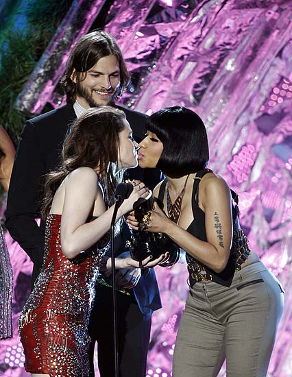 Kristen Stewart, left, accepts the award for best female performance from presenter Nicki Minaj at the MTV Movie Awards on Sunday, June 5, 2011, in Los Angeles. IN background is presenter Ashton Kutcher. (AP Photo/Matt Sayles)
