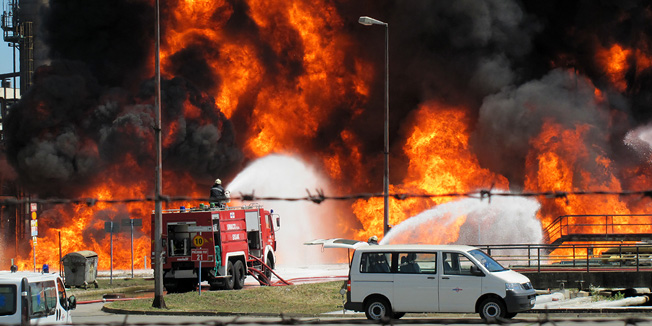 Sisak, 200611.U ponedjeljak 20. lipnja oko 10.30 sati izbio je pozar u Rafineriji nafte Sisak. Pozar je najprije izbio na produktovodu izmedju spremnika goriva i najveceg rafinerijskog postrojenja KP-6, a uskoro se prosirio na cijeli produktovod i ozbiljno prijeti postrojenju krekinga u rafineriji i najblizim spremnicima goriva. Evakuiraju se radnici iz rafinerije i dio stanovnistva najblizi Rafineriji, jer se oko 11.30 sati pozar  opasno priblizio postrojenjima za preradu nafte i spremnicima koje rafinerijski radnici nastoje zaustaviti i zastiti hladjenjem. Plameni jezici sezu preko 50 metara u zrak, a oblaci crnmog dima nadvili su Sisak. Foto: Mate Piskor / CROPIX                         