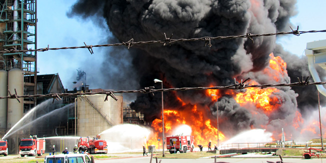 Sisak, 200611.Oko 10.30 sati izbio je pozar u Rafineriji nafte Sisak. Pozar je najprije izbio na produktovodu izmedju spremnika goriva i najveceg rafinerijskog postrojenja KP-6, a uskoro se prosirio na cijeli produktovod i ozbiljno prijeti postrojenju krekinga u rafineriji i najblizim spremnicima goriva. Evakuiraju se radnici iz rafinerije i dio stanovnistva najblizi Rafineriji, jer se oko 11.30 sati pozar  opasno priblizio postrojenjima za preradu nafte i spremnicima koje rafinerijski radnici nastoje zaustaviti i zastiti hladjenjem. Plameni jezici sezu preko 50 metara u zrak, a oblaci crnmog dima nadvili su Sisak. Foto: Mate Piskor / CROPIX                         