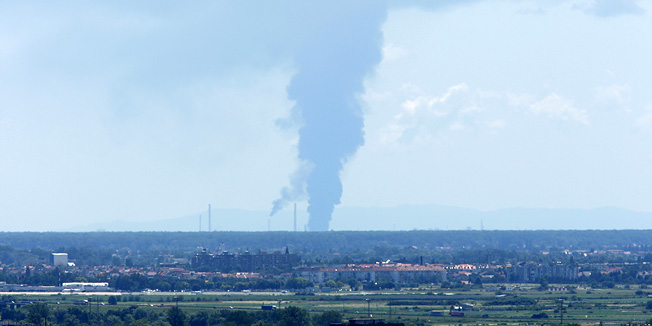 Zagreb, 200611.Oko 10.30 sati izbio je pozar u Rafineriji nafte Sisak. Pozar je najprije izbio na produktovodu izmedju spremnika goriva i najveceg rafinerijskog postrojenja KP-6, a uskoro se prosirio na cijeli produktovod i ozbiljno prijeti postrojenju krekinga u rafineriji i najblizim spremnicima goriva. Evakuiraju se radnici iz rafinerije i dio stanovnistva najblizi Rafineriji, jer se oko 11.30 sati pozar  opasno priblizio postrojenjima za preradu nafte i spremnicima koje rafinerijski radnici nastoje zaustaviti i zastiti hladjenjem. Plameni jezici sezu preko 50 metara u zrak, a oblaci crnmog dima nadvili su Sisak. Na slici: dim iz rafinerije snimljen iz Vukovarske ulice u Zagrebu.Foto: Davor Pongracic / CROPIX                         