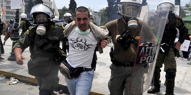Riot police detain a protester as they clash with demonstrators during a 48-hour general strike in Athens on June 29, 2011.   Greek lawmakers voted Wednesday for a massive new austerity package demanded by international creditors, amid violent clashes between protesters and police firing tear gas outside the parliament. AFP PHOTO / ARIS MESSINIS