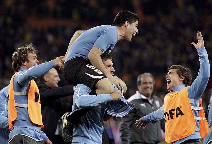 Uruguay's Sebastian Eguren carries Luis Suarez (top) as they celebrate after the team won a penalty shootout against Ghana in a 2010 World Cup quarter-final soccer match at Soccer City stadium in Johannesburg July 2, 2010.      REUTERS/Henry Romero (SOUTH AFRICA  - Tags: SPORT SOCCER WORLD CUP)