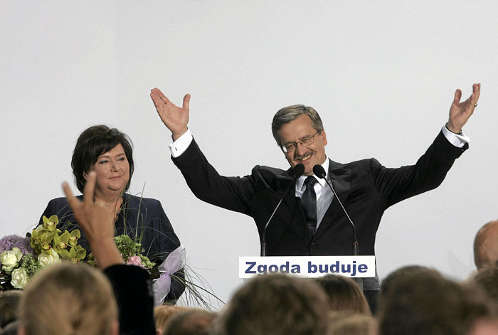 Poland's acting President Bronislaw Komorowski, speaker of the parliament and presidential candidate from Civic Platform Party (PO) waves to supporters next to his wife Anna at his election headquarters in Warsaw, July 4, 2010. Komorowski, candidate of Poland's ruling pro-business party, Civic Platform (PO), won Sunday's presidential election, exit polls showed. The text reads: 'Consensus building.'  REUTERS/Wojciech Olkusnik/Agencja Gazeta (POLAND - Tags: POLITICS ELECTIONS) POLAND OUT. NO COMMERCIAL OR EDITORIAL SALES IN POLAND