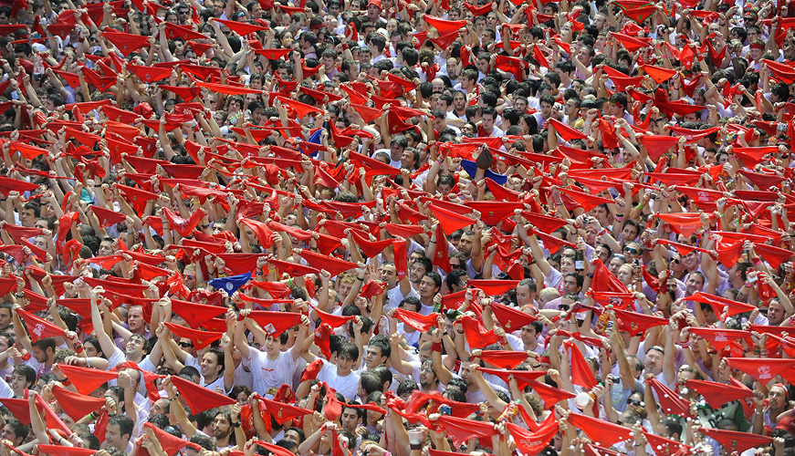 Participants hold traditional red scarves during the 'Chupinazo' to mark the start at noon sharp of the San Fermin Festival on July 6, 2010 in front of the Town Hall of Pamplona, northern Spain. The festival is a symbol of Spanish culture, despite heavy condemnation from animal rights groups, and attracts thousands of tourists to watch the bull runs.  AFP PHOTO / ANDER GILLENEA