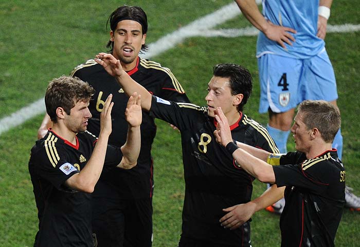 Germany's midfielder Thomas Mueller (L) celebrates with Germany's midfielder Sami Khedira (back, L), Germany's midfielder Mesut Ozil (C) and Germany's midfielder Bastian Schweinsteiger after scoring the opening goal during the 2010 World Cup third place football match Uruguay vs. Germany on July 10, 2010 at Nelson Mandela Bay stadium in Port Elizabeth. NO PUSH TO MOBILE / MOBILE USE SOLELY WITHIN EDITORIAL ARTICLE -      AFP PHOTO / CARL DE SOUZA