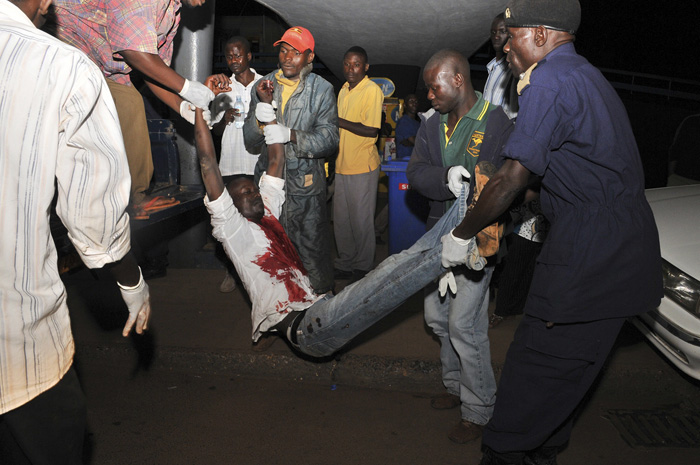 People carry a man, injured in an explosion, upon his arrival at the Mulago Hospital in Kampala July 12, 2010. Two separate explosions killed at least 23 people packed into bars in the Ugandan capital Kampala to watch the World Cup final on Sunday night, police said. REUTERS/Ronald Kabuubi (UGANDA - Tags: CIVIL UNREST SPORT SOCCER WORLD CUP IMAGES OF THE DAY)