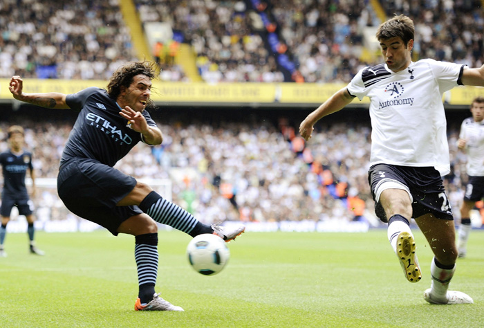 Tottenham Hotspur's Vedran Corluka (R) blocks a shot on goal by Manchester City's Carlos Tevez during their English Premier League soccer match at White Hart Lane in London August 14, 2010. REUTERS/Dylan Martinez  (BRITAIN - Tags: SPORT SOCCER) NO ONLINE/INTERNET USAGE WITHOUT A LICENCE FROM THE FOOTBALL DATA CO LTD. FOR LICENCE ENQUIRIES PLEASE TELEPHONE ++44 (0) 207 864 9000
