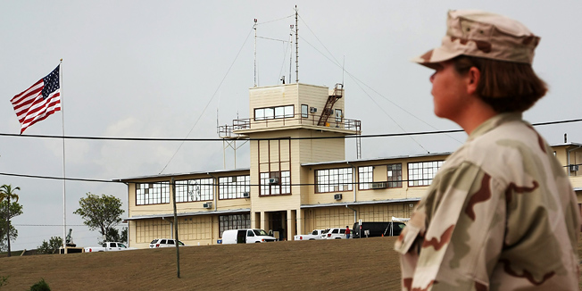 A U.S. Navy personnel walks past the military commission courthouse on Sunday, Aug. 8, 2010, where Canadian citizen Omar Khadr is set to be tried for war crimes at Guantanamo Bay, Cuba. The first war-crimes trial of the Obama administration is slated to start this week as Omar Khadr fights a desperate battle to stave off a possible life behind bars. (AP Photo/The Canadian Press, Colin Perkel)