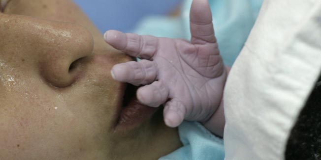 Jenny Guzman kisses the hand of her newborn baby, Kalel, after delivering him at Lima's maternity hospital May 3, 2010. Peruvians will celebrate Mother's Day on Sunday. REUTERS/Mariana Bazo  (PERU - Tags: HEALTH SOCIETY)