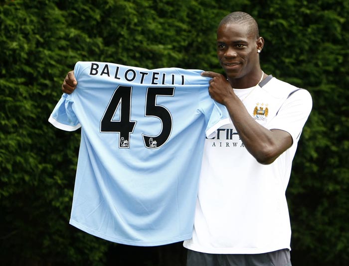 ** CORRECTS LOCATION TO CARRINGTON TRAINING GROUND **Manchester City's new signing Mario Balotelli holds up his shirt after a press conference held at the Carrington training ground, Manchester, England, Tuesday Aug. 17, 2010. Balotelli was signed from Inter Milan. (AP Photo/Tim Hales)