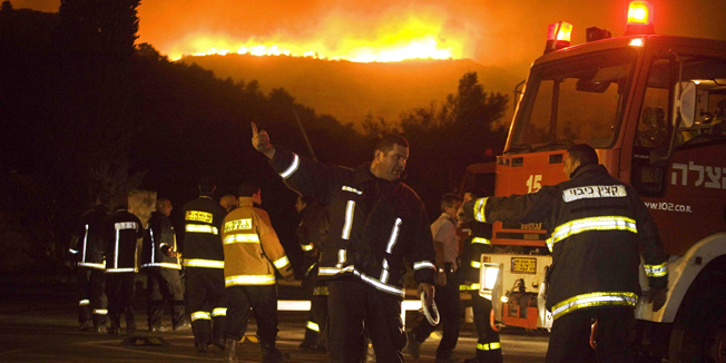 Firefighters try to prevent a widfire from reaching the town of Tirat Hacarmel, northern Israel, Thursday, Dec. 2, 2010. A massive forest fire that scorched part of northern Israel killed scores of people Thursday, officials said. Fire officials said the blaze, which torched some 800 acres (325 hectares), remained out of control as nightfall arrived. (AP Photo/Dan Balilty)