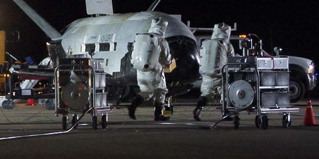 This picture provided by the US Air Force shows personnel inspecting the X-37B, the Air Force's first unmanned re-entry spacecraft, after landing on December 3, 2010 at Vandenberg Air Force Base in California. The X-37B, named Orbital Test Vehicle 1 (OTV-1), conducted on-orbit experiments for more than 220 days during its maiden voyage, and fired its orbital maneuver engine in low-earth orbit to perform an autonomous reentry before landing, according to the Air Force.         AFP PHOTO/US AIR FORCE/HO       ++RESTRICTED TO EDITORIAL USE  NOT FOR SALE FOR MARKETING OR ADVERTISING CAMPAIGNS++