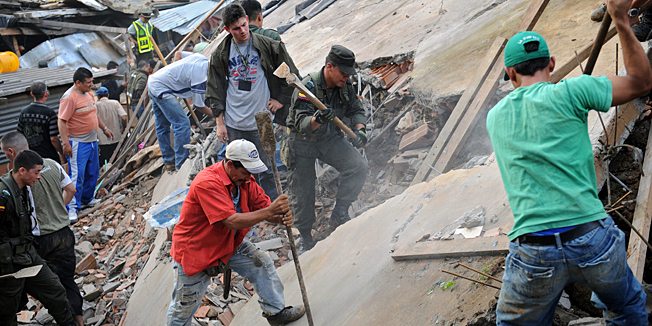 Colombian soldiers and residents remove rubble to find survivors following a landslide in La Gabriela neighborhood, north of Medellin, department of Antioquia, Colombia, on December 5, 2010, after heavy storms. At least one person died and 200 are missing after a mudslide triggered by heavy rains. Rains affecting Colombia have killed 176 people and left 1,500,000 affected so far this year, and the intensification of rains in recent days has forced to declare emergency in several regions.  AFP PHOTO/Raul ARBOLEDA