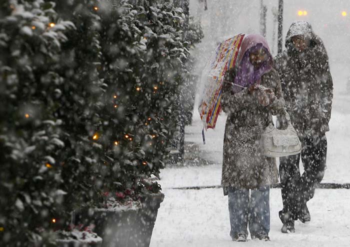 Pedestrians walk during a snow-fall in central London, Saturday, Dec. 18, 2010. Plunging temperatures and heavy snow saw large swathes of Britain grind to a standstill, as London's Gatwick Airport closed its runway and British Airways cancelled flights at Heathrow. (AP Photo/Alastair Grant)