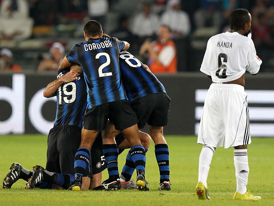 TP Mazembe's Mukok Kanda walks past Inter Milan's players as they celebrate after winning the 2010 FIFA Club World Cup final football match at Zayed Sports City in the Emirati capital Abu Dhabi on December 18, 2010. Inter won 3-0. AFP PHOTO/KARIM SAHIB