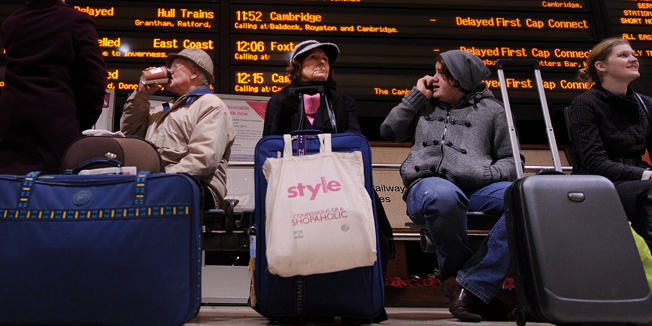 Passengers sit underneath an electronic information board showing cancelled and delayed trains, at Kings Cross train station in London, on December 21, 2010.  Thousands of angry travellers forced to sleep in airports and train stations across Europe faced more misery Tuesday as fresh snowfalls paralysed transport systems just days before Christmas.    London Heathrow, Europe's busiest airport, was only operating about a third of its normal schedule during a fourth day of disruption, while Frankfurt halted all flights after a new blanketing of snow.             AFP PHOTO/BEN STANSALL