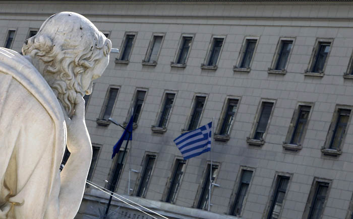 A Greek flag at the Bank of Greece is seen near a statue of ancient philosopher Socrates in Athens February 5, 2010. Greece sought on Friday to overcome sceptics about its commitment to slashing its massive fiscal deficit, promising to push through tax laws and other measures to achieve its debt reduction targets.   REUTERS/Yiorgos Karahalis (GREECE - Tags: BUSINESS SOCIETY)