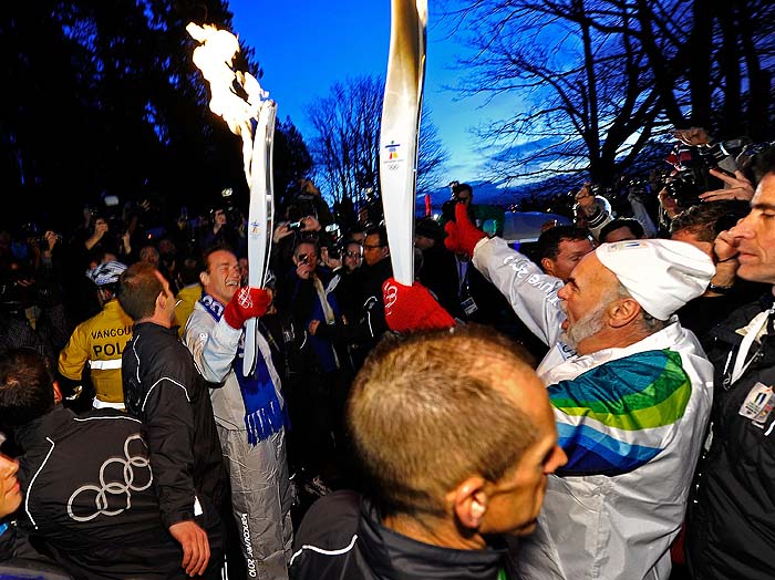 VANCOUVER, BC - FEBRUARY 12: California Governor Arnold Schwarzenegger lights the Olympic flame from a runner as he prepares to run with the torch during the Olympic torch relay ahead of the Vancouver 2010 Winter Olympics on February 12, 2010 in Vancouver, Canada.   Kevork Djansezian/Getty Images/AFP== FOR NEWSPAPERS, INTERNET, TELCOS & TELEVISION USE ONLY ==