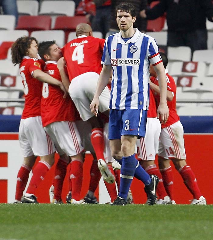 Hertha Berlin's Arne Friedrich (3) looks on as Benfica's players celebrate Oscar Cardozo's goal during their Europa League soccer match at Luz stadium in Lisbon February 23, 2010. REUTERS/ Nacho Doce (PORTUGAL - Tags: SPORT SOCCER)