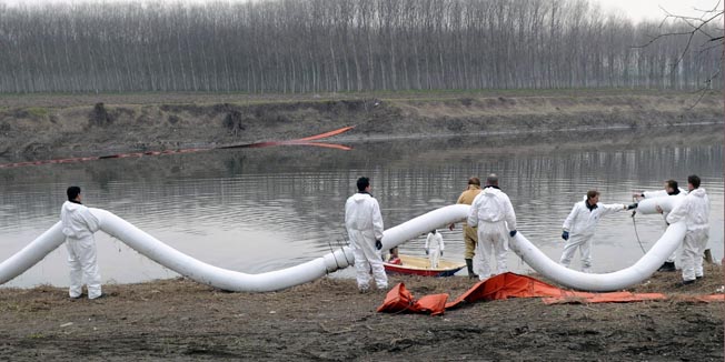 Italian environment protection workers lay a barriers across the Lambro river to try and contain thousands of tonnes of diesel and other fuel near Orio Litta village, about 50 km from Milan, February 25, 2010. The Lombardy and Emilia Romagna regions in northern Italy asked Rome to declare a state of emergency to help deal with the spill, that authorities said could have been a deliberate act of pollution, in the Po and its Lambro tributary in the country's richest industrial and agricultural area.  REUTERS/Paolo Bona      (ITALY - Tags: DISASTER ENVIRONMENT)
