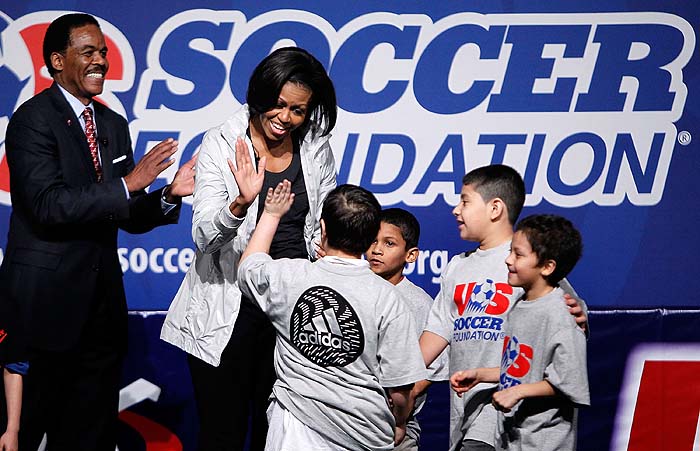 WASHINGTON - MARCH 05: U.S. first lady Michelle Obama (2nd L) hi-fives with local school kids as US Soccer Foundation President and CEO Ed Foster-Simeon (L) looks on during a youth soccer clinic March 5, 2010 in Washington, DC. The clinic is to promote the national fight against childhood obesity and in support for the first lady's 
