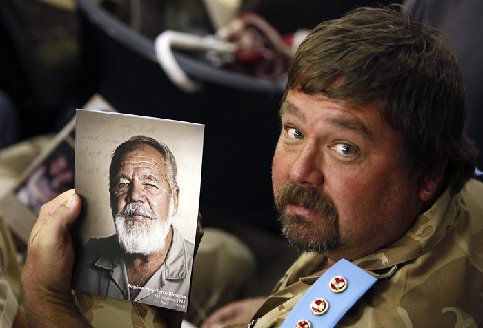 A supporter of white supremacist leader Eugene Terre'blanche holds his picture during his funeral in Ventersdorp in South Africa's North West Province April 9, 2010.Thousands of followers of the murdered leader, many wearing combat fatigues, thronged to his funeral on Friday as racial tensions ran high. Two black farm workers have been charged with beating and hacking Terre'blanche to death last Saturday in what police suspect was a pay dispute, but which his party sees as politically motivated.   REUTERS/Siphiwe Sibeko (SOUTH AFRICA - Tags: OBITUARY CRIME LAW POLITICS)